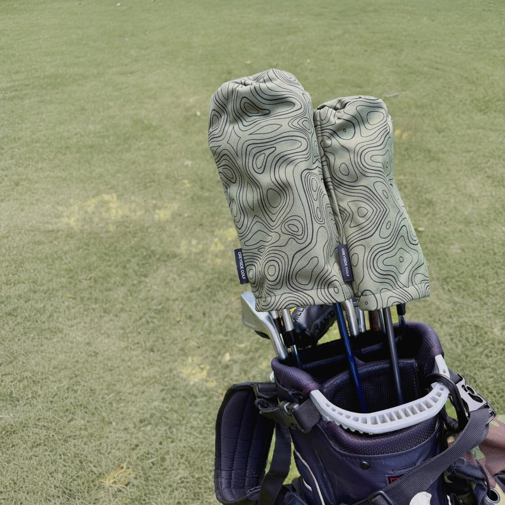 The Azimuth green topographic headcovers on driver and wood in golf bag on course