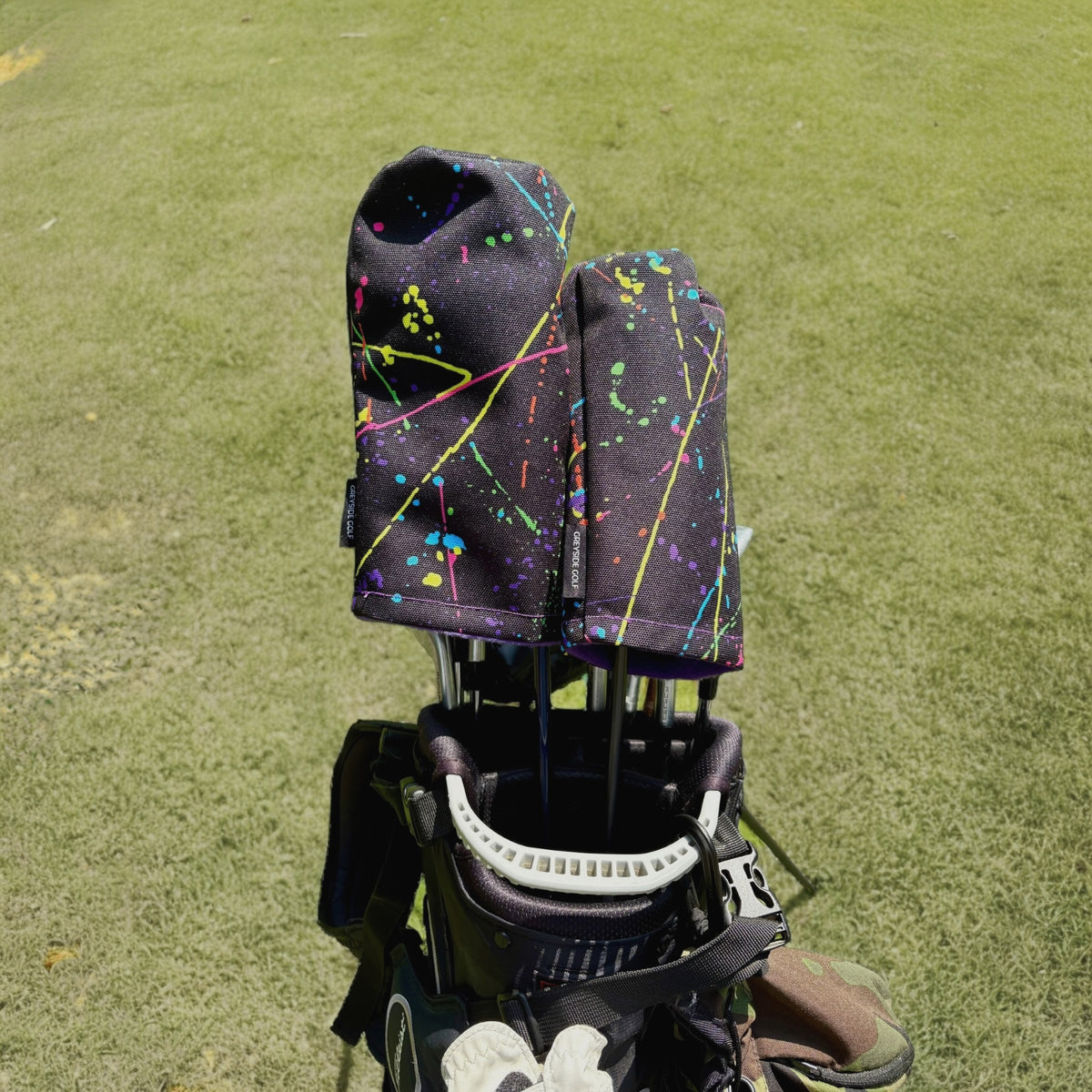 The Splatter Job neon splatter paint headcovers on driver and wood in golf bag on course