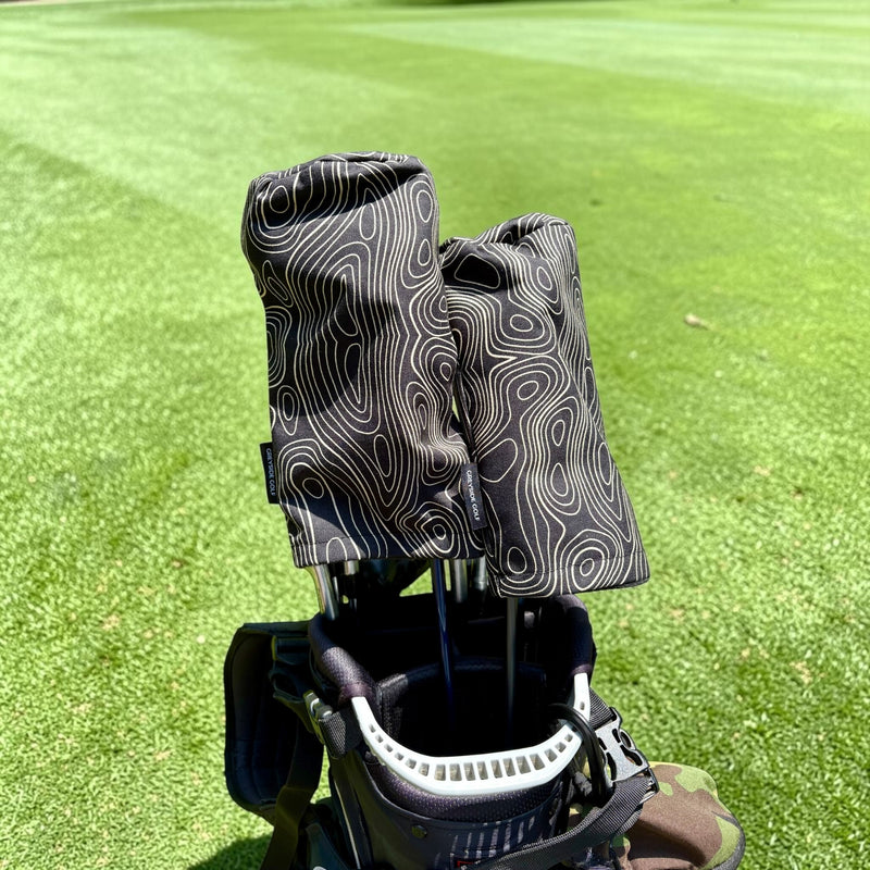 The Azimuth black topographic headcovers on driver and wood in golf bag on course