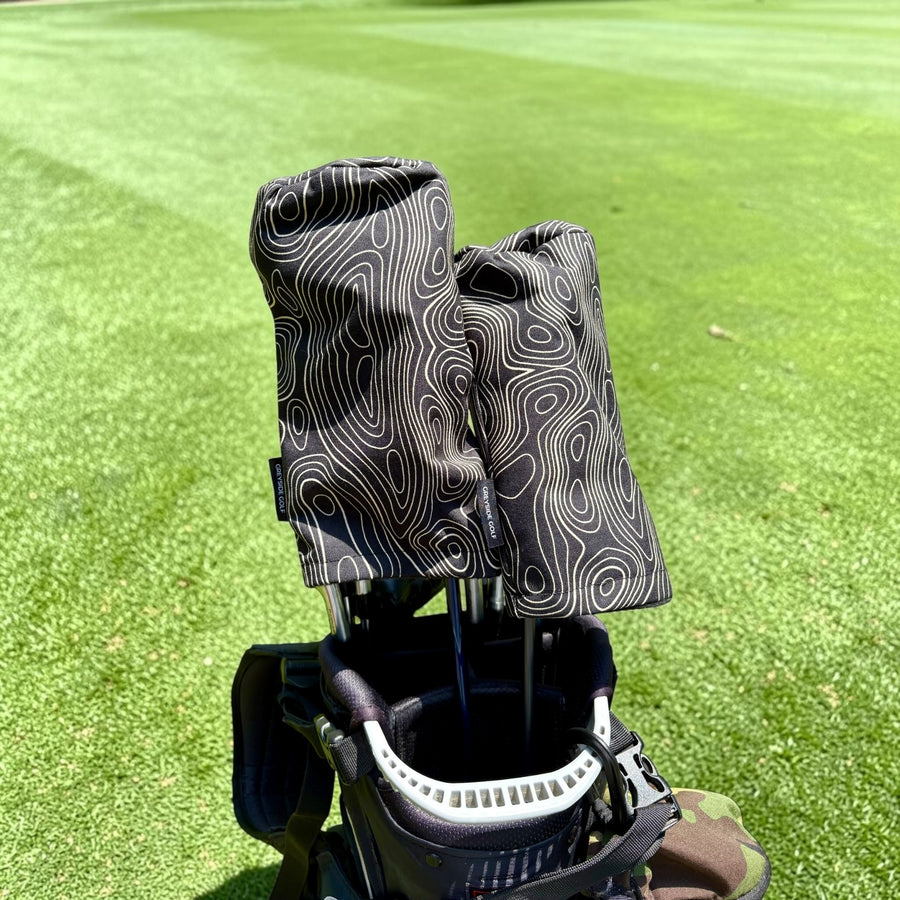 The Azimuth black topographic headcovers on driver and wood in golf bag on course